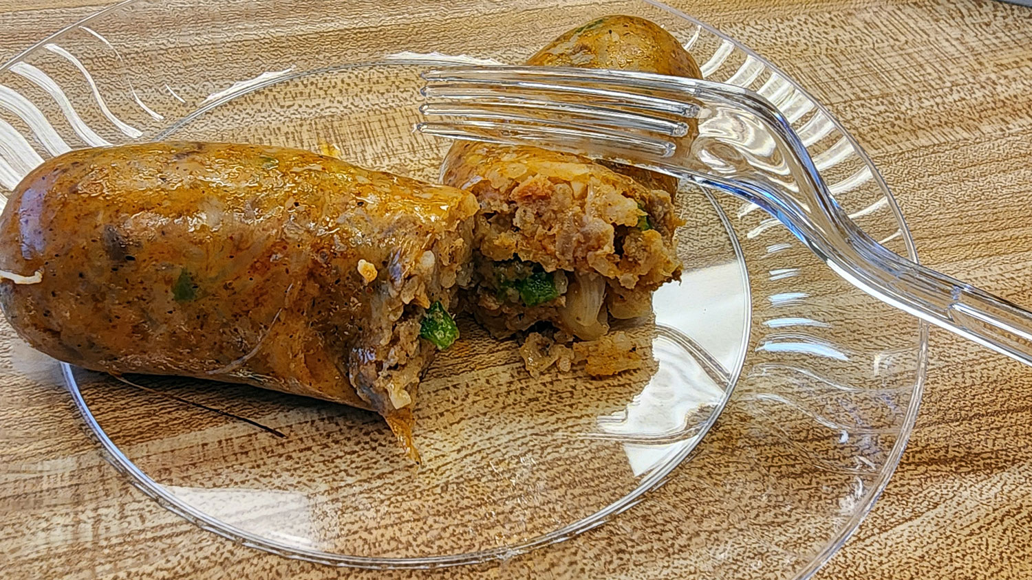 A boudin sausage cut in half with a plastic fork