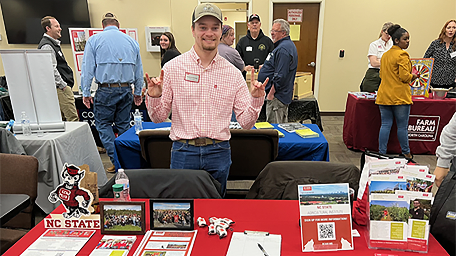 a man stands at a table with booklets and flyers for the Agricultural Institute