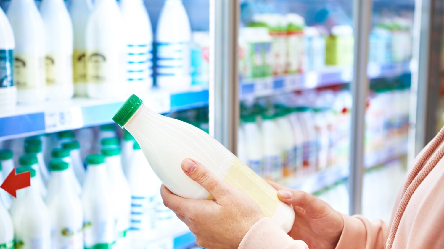 a hand holding milk in a grocery store